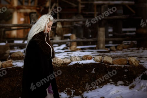 Preview: Beautiful blonde Viking dressed in a black cloak against the backdrop of the castle