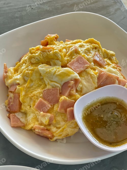 Preview: Omelette with pork bacon cutted on rice and sauce on white ceramic plate and spoon and fork.