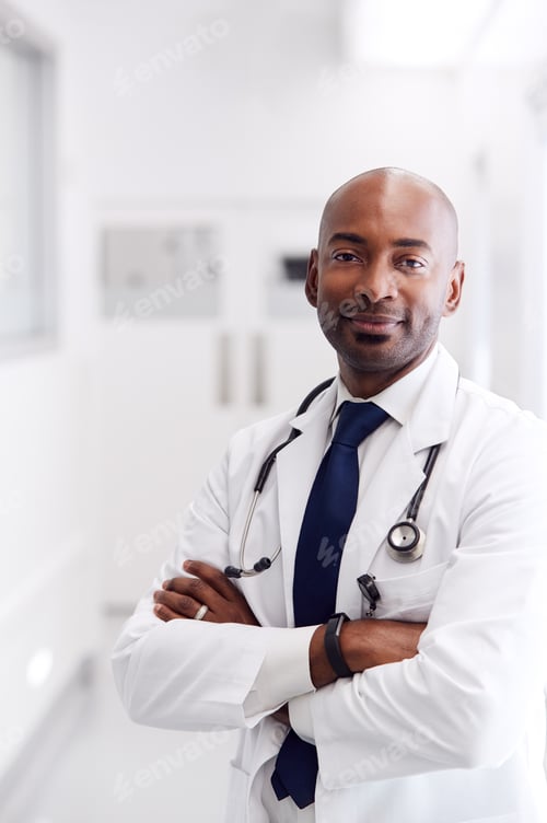 Preview: Portrait Of Mature Male Doctor Wearing White Coat Standing In Hospital Corridor