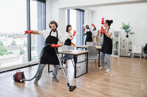 Preview: Caucasian man with modern vacuum cleaner and three cleaners dancing.