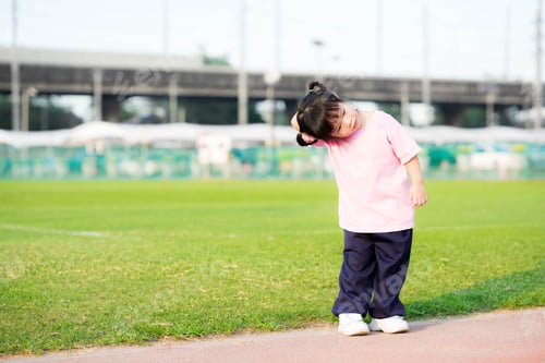 Preview: Cute 4 year old Asian girl standing for exercise. Child embraces his arms across the head.