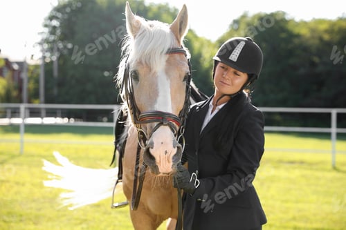 Preview: Young woman in horse riding suit and her beautiful pet outdoors on sunny day