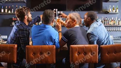 Preview: Rear View Of Male Friends Watching Game In Sports Bar Celebrating Team Win