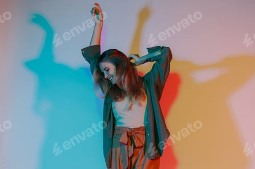 Preview: Young woman dancing with colorful lights on wall