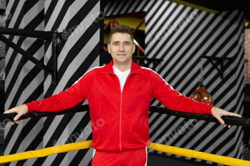 Preview: Man in a red tracksuit poses and has fun in the boxing ring.