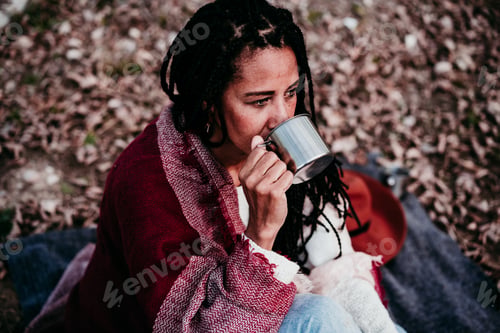Preview: Woman Drinks from Cup Outdoors Wrapped in Blanket