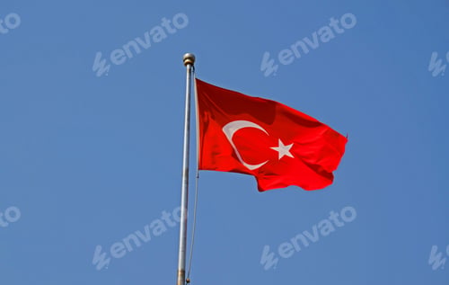 Preview: Turkish national flag on blue sky background. The flag on a flagpole flutters in the wind.