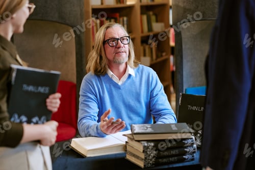 Preview: Middle Aged Caucasian Man Signing Books during Presentation Event in Library