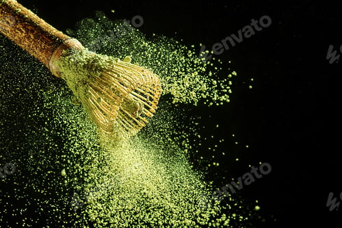 Preview: Bamboo whisk with flying matcha tea powder on a black background.