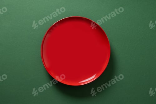 Preview: Red empty plate on green background. Christmas table setting. Xmas celebration.