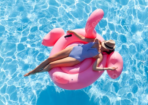 Preview: Woman relaxing on pink flamingo inflatable ring