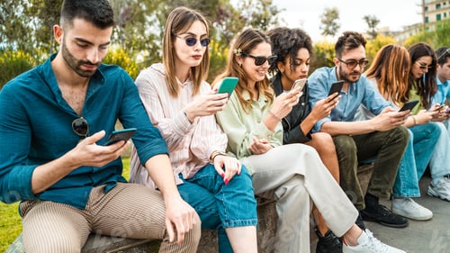 Preview: Diverse group of young people using smartphones outdoors in park, social media addiction