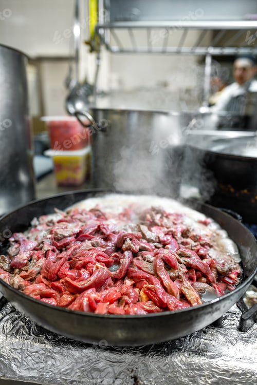 Preview: Meat fryed on frying pan on modern stove in professional kitchen