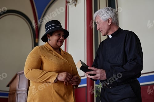 Preview: Believer woman talking to priest in church