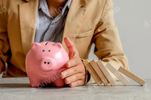 Preview: Businessman Shielding Pink Piggy Bank From Falling Dominoes