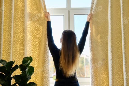 Preview: Young woman closing opening thick curtains on window