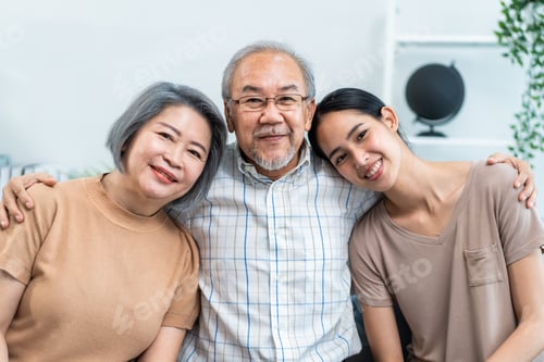 Preview: Portrait of Asian senior couple sitting on sofa with daughter in house.