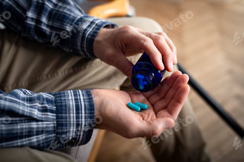 Preview: Middle aged caucasian man taking pills sitting on sofa at home