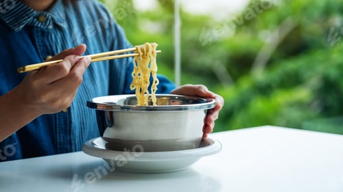 Preview: Closeup image of a woman eating asian style instant noodle at home