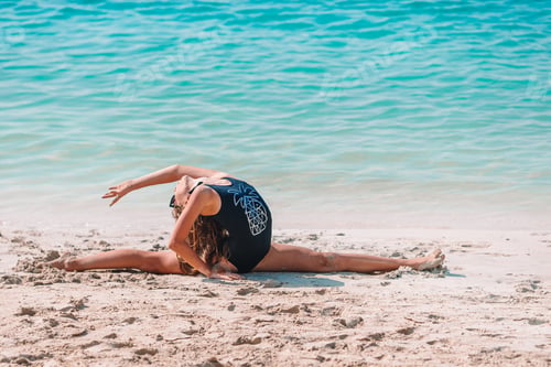 Preview: Active little girl at beach having a lot of fun. Cute kid making sporty exercises on the seashore