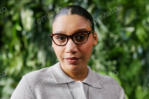Preview: Portrait of Black Woman Wearing Glasses Standing against Plant Wall