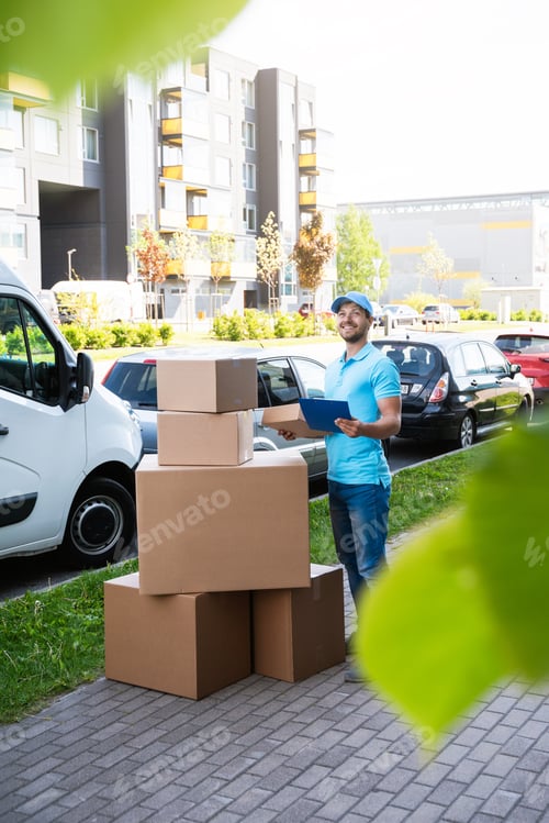 Preview: Happy delivery man with a lot of cardboard boxes near his van