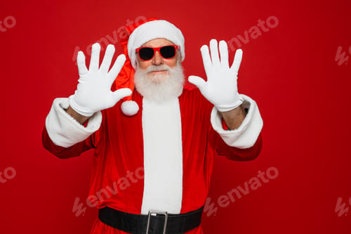 Preview: Happy Santa Claus sunglasses waving hands looking camera isolated red background headshot portrait