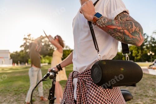 Preview: company of friends having fun together in park listening to music