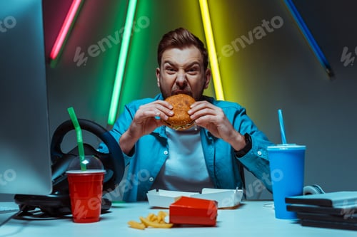 Preview: handsome and good-looking man eating burger and looking at camera