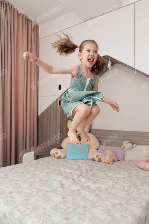 Preview: Cute girl jumping on the bed in the room