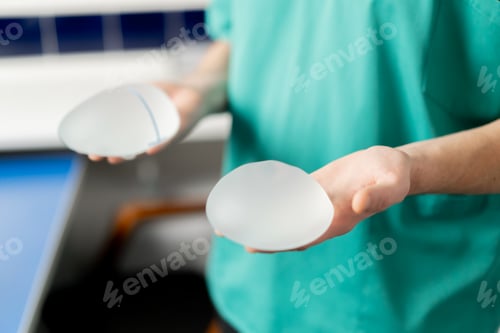 Preview: close-up in a plastic surgery clinic a doctor holds two different implants in his hands