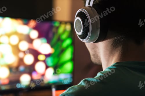 Preview: Image of focused man in headphones playing video game on computer