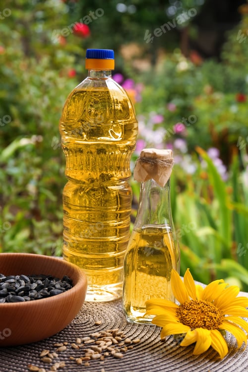 Preview: Bottles of sunflower oil and seeds in bowl on table outdoors