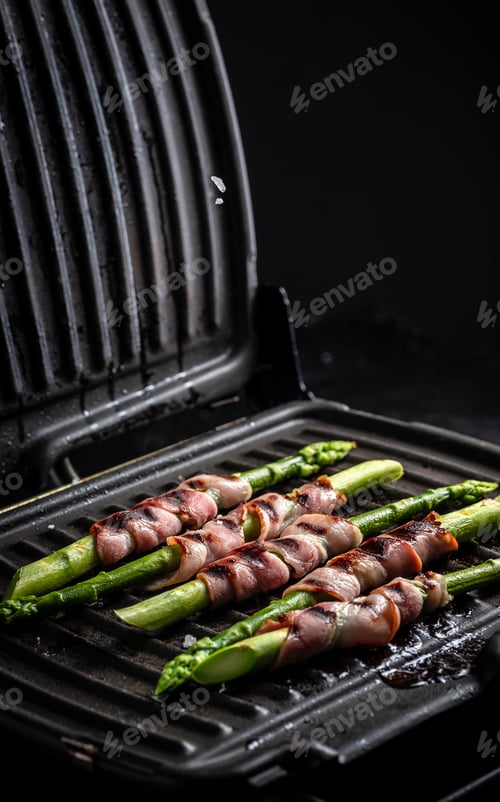 Preview: Asparagus baked with bacon on an electric grill, vertical image, place for text