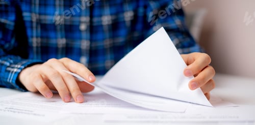 Preview: a hand holding a document sheet, doing some paper work in the office sitting at the table wide web