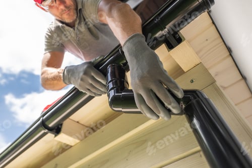 Preview: Worker Installing Gutter System on Roof