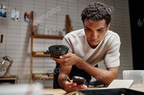 Preview: analog film development, dark skinned man meticulously times the process in a darkroom