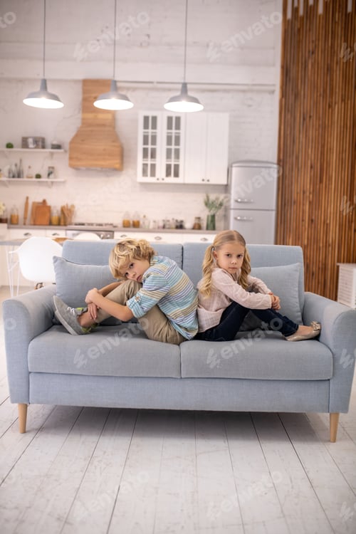 Preview: Kids sitting back to back and hugging knees