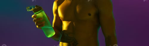 Preview: Close up of sporty man with muscled naked torso holding bottle with water on studio
