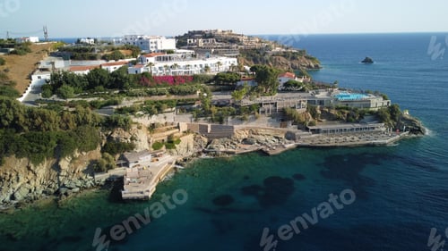 Preview: Aerial view of a coastal town with turquoise waters framed by lush green trees on the shoreline