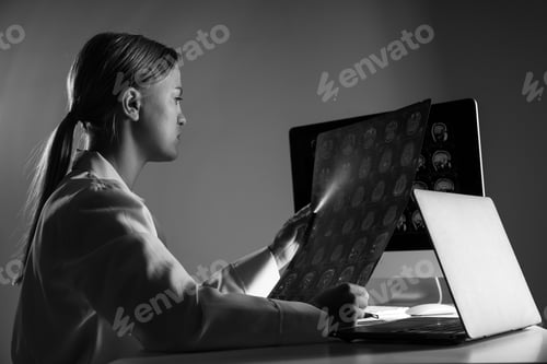 Preview: A young female doctor looks at an MRI image of a human head. Black and white photo