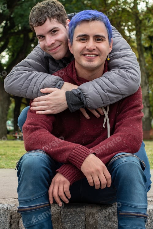 Preview: Gay male couple hugging and looking at camera outdoors