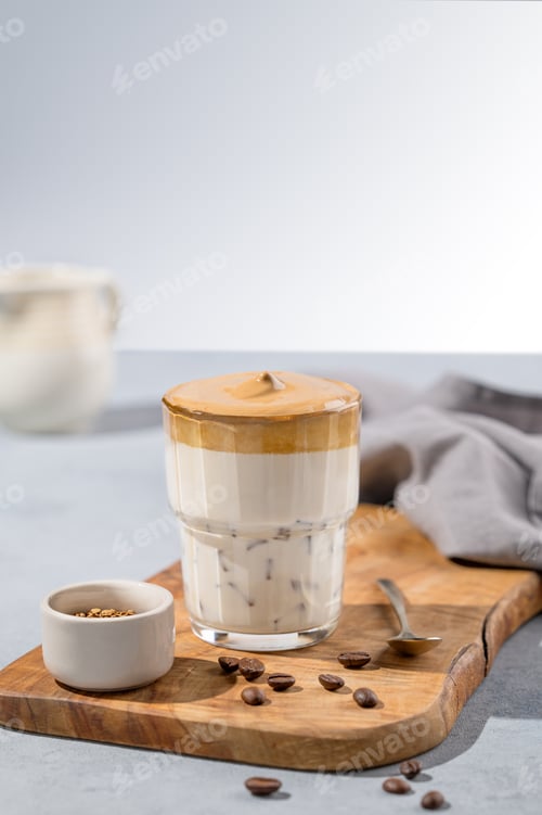 Preview: Dalgona coffee. Whipped instant coffee in a glass on a wooden board with coffee beans