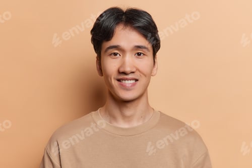 Preview: Portrait of handsome dark haired man smiles positively dressed in casual t shirt being satisfied
