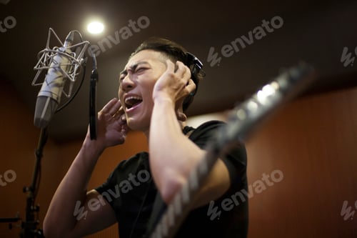 Preview: Young man singing with guitar in recording studio