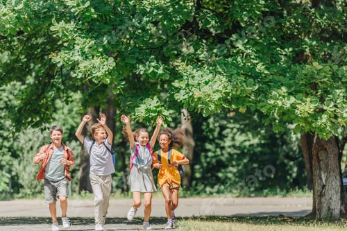 Preview: four happy multicultural schoolkids gesturing with raised hands while running in park