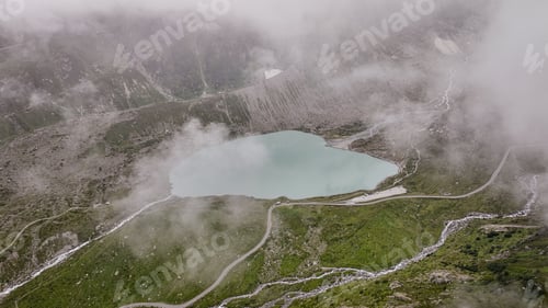 Preview: Beautiful lake surrounded by mountains and mist in Steinsee Switzerland during midday