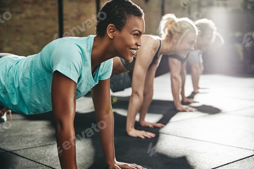 Preview: Young woman smiling while doing pushups at the gym