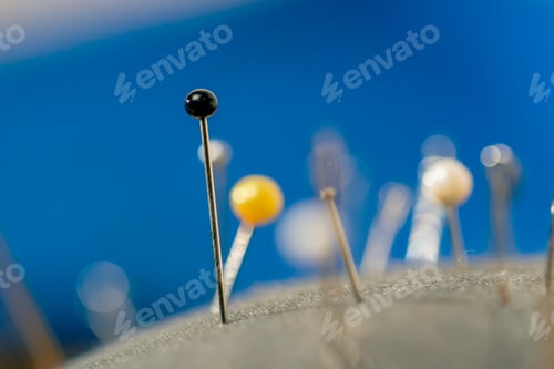 Preview: super close-up in a sewing workshop pin cushion is covered with needles and pins