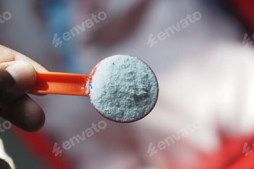 Preview: Measuring powder with a red scoop in bright light